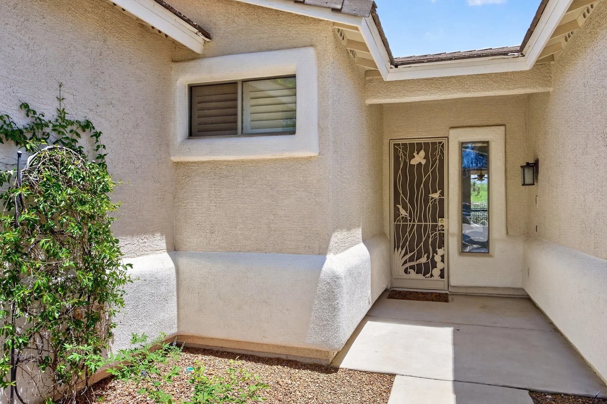 Shaded front entrance with wrought-iron security door and courtyard
