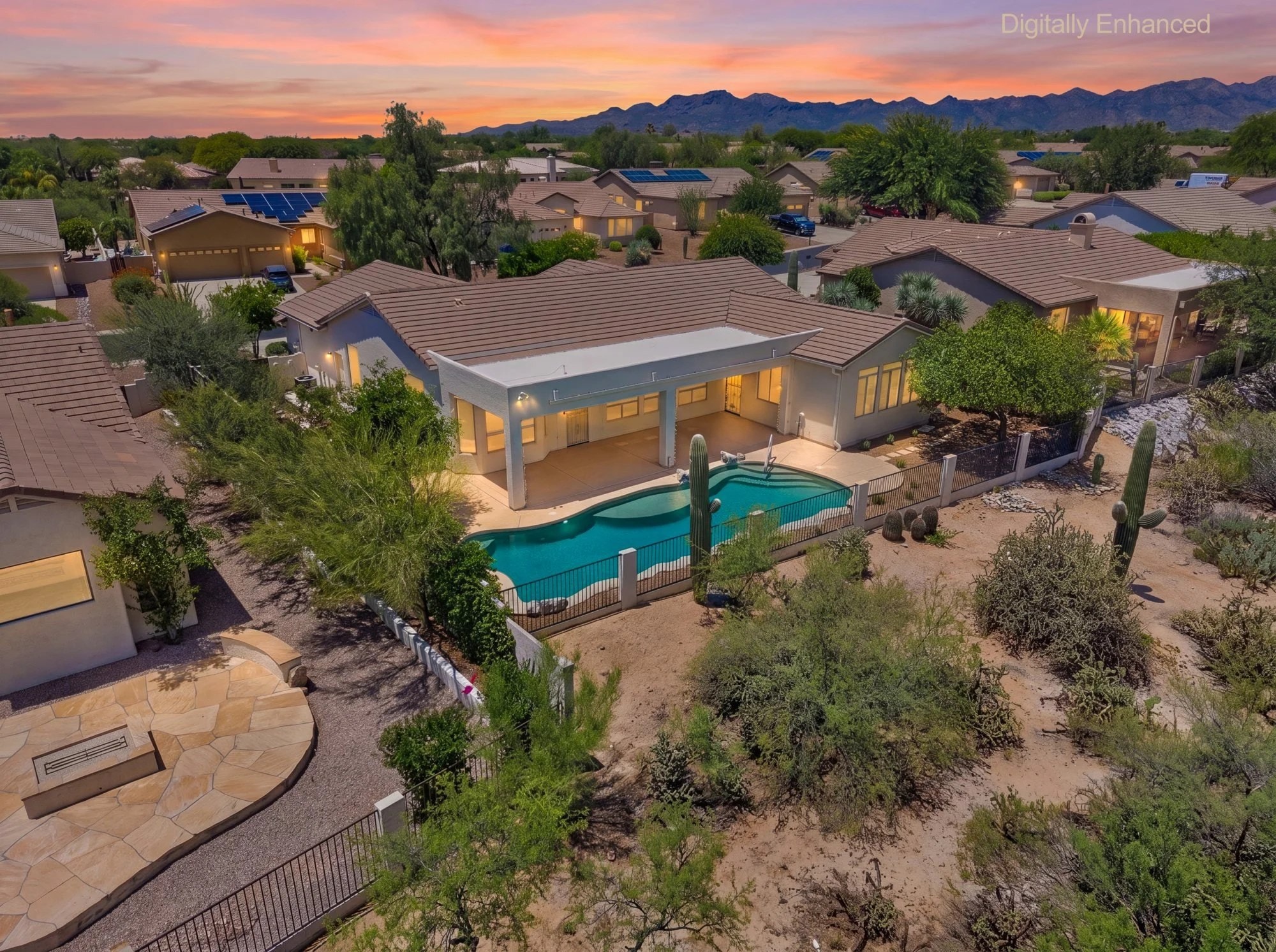 Aerial twilight view of the lit pool and covered patio with the Catalina Mountains at sunset