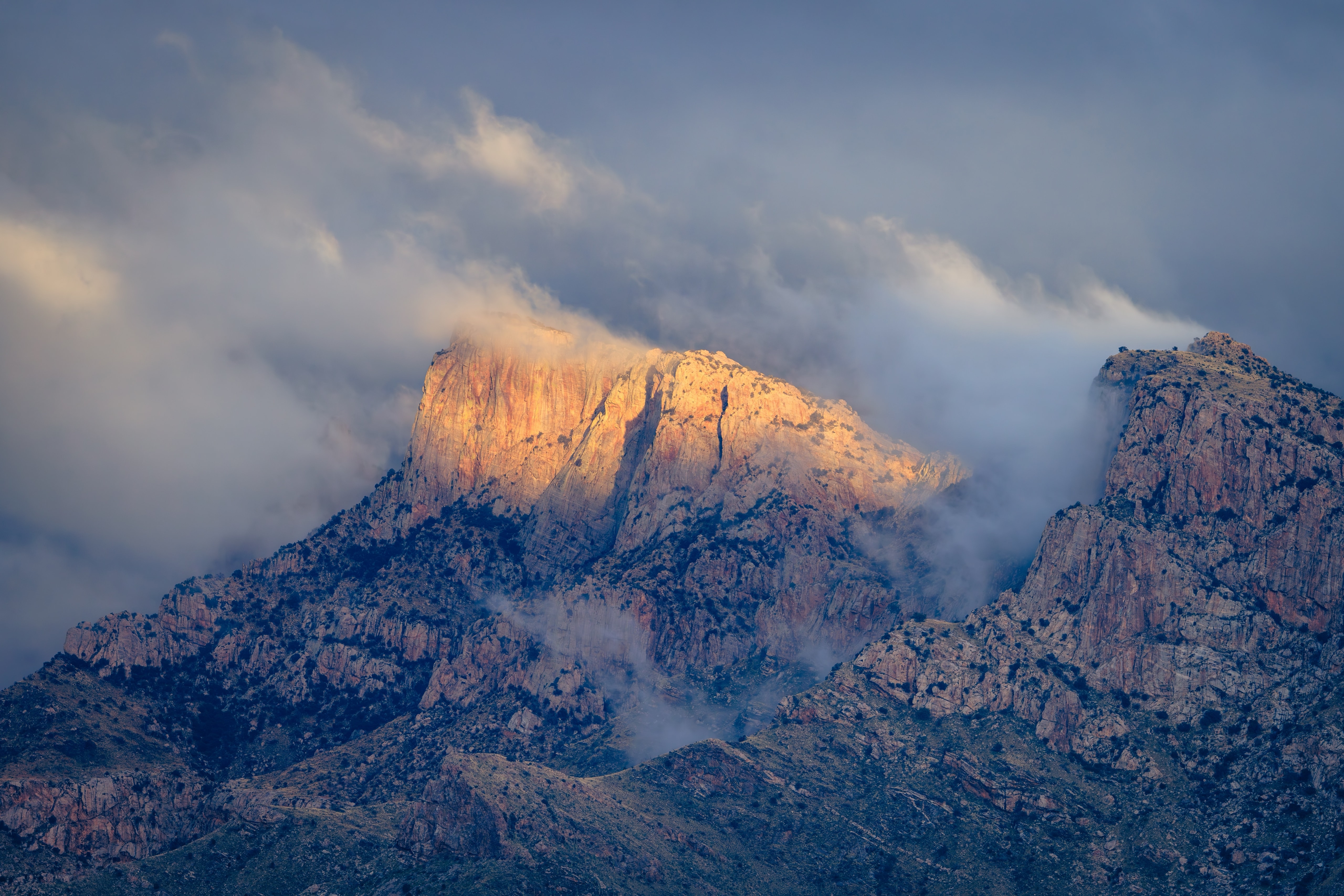 Table Mountain on Pusch Ridge in the Santa Catalina Mountains, lit gold through storm clouds above Tucson