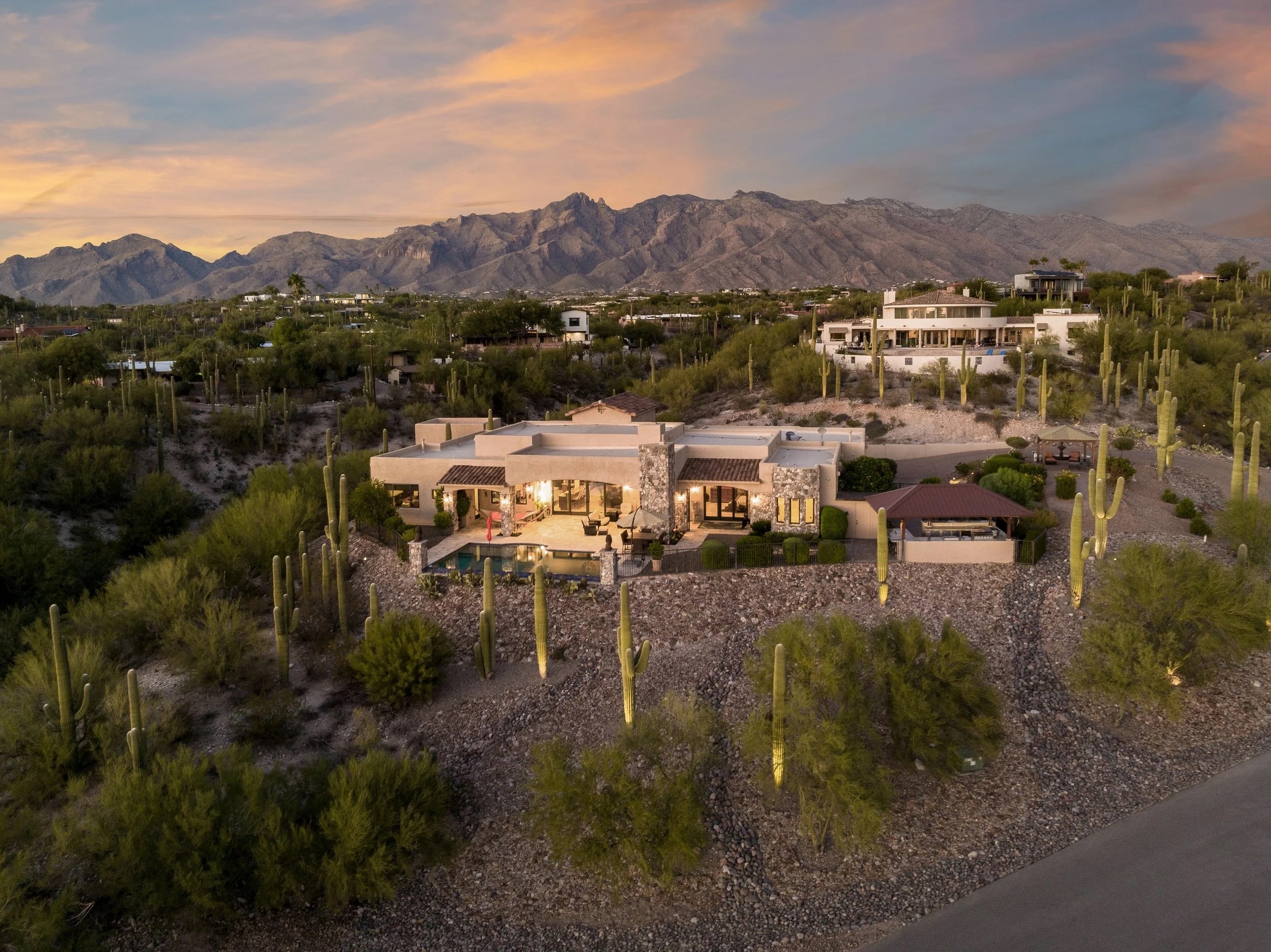 A Tucson estate at dusk among saguaros, with the Santa Catalina Mountains behind